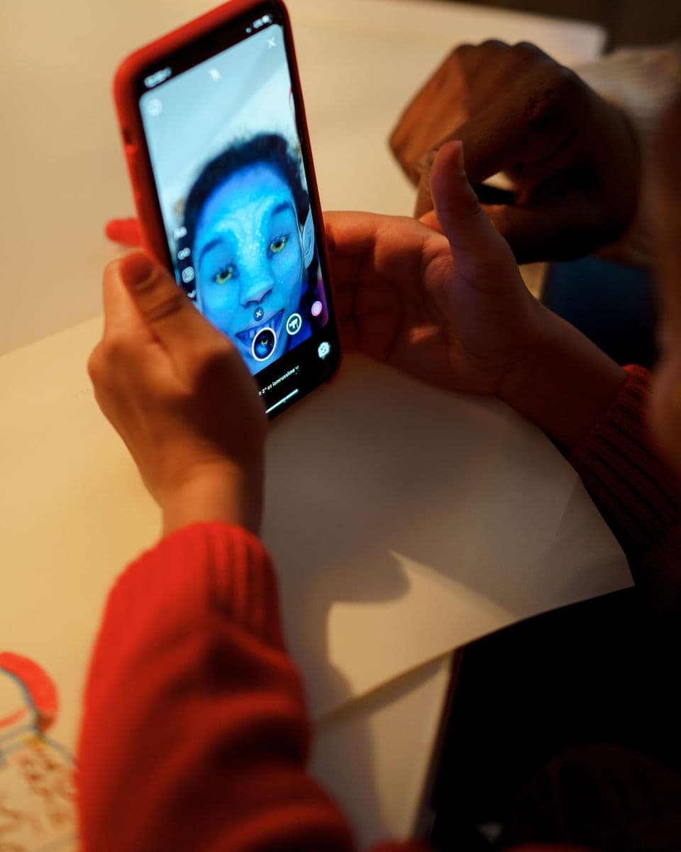 Close-up of hands holding a phone on a video call, a child's laughing face on the screen.